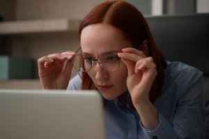 Kuvituskuva, jossa nainen katsoo silmälasiensa läpi tietokoneen näyttöä.