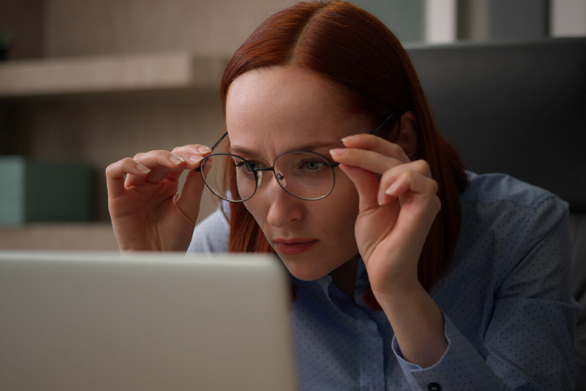 Kuvituskuva, jossa nainen katsoo silmälasiensa läpi tietokoneen näyttöä.